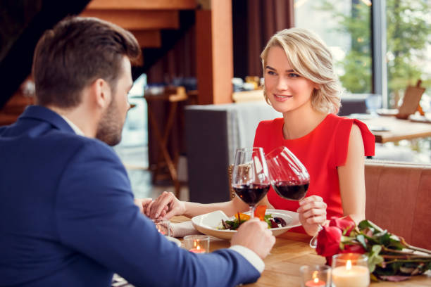 istock Young couple on date in restaurant sitting having lunch drinking wine holding hands looking at each other passionate 1131884354