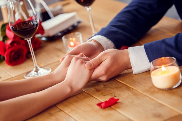 istock Young couple on date in restaurant sitting drinking wine holding hands close-up 1131884362