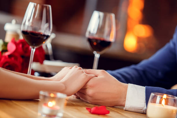 istock Young couple on date in restaurant sitting drinking wine holding hands tender 1131884367