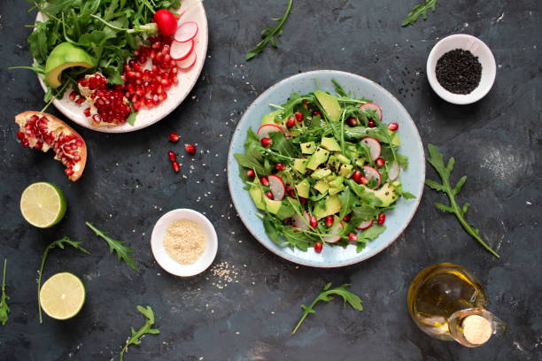 istock Ingedient for making salad on dark background. Vegetable salad in plate, avocado, arugula, pomegranate, radish and sesame. 1131884519