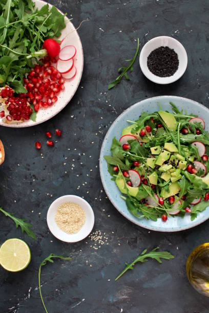 istock Ingedient for making salad on dark background. Vegetable salad in plate, avocado, arugula, pomegranate, radish and sesame. 1131884566