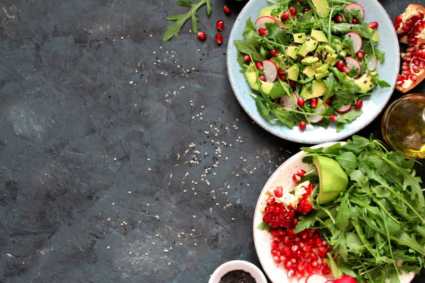 istock Ingedient for making salad on dark background. Vegetable salad in plate, avocado, arugula, pomegranate, radish and sesame. 1131884667