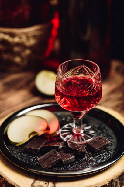 Homemade red currant nalivka and chocolate with apple Homemade red currant nalivka and chocolate with sliced apple on metal tray nalewka stock pictures, royalty-free photos & images