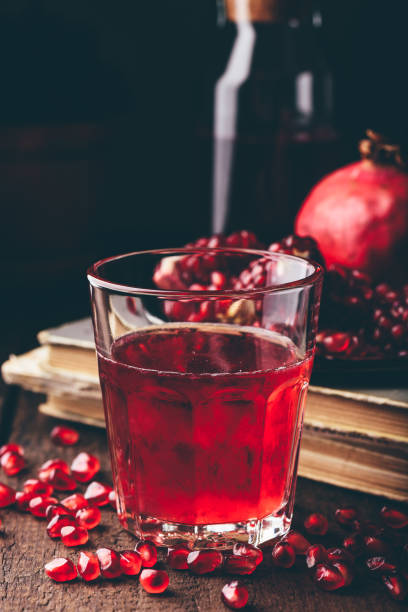 Drinking glass with pomegranate cocktail Drinking glass with pomegranate cocktail on wooden table nalewka stock pictures, royalty-free photos & images