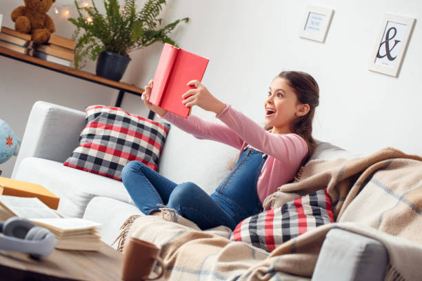Little girl at home sitting holding book surprised