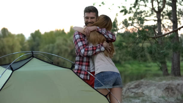 istock Couple embracing, putting up tent, great teamwork, wilderness survival school 1131888614