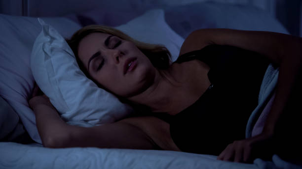 Beautiful female sleeping on bed at night, resting after hard working day, snore