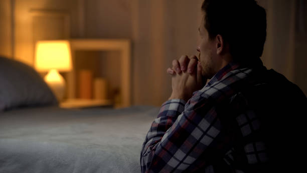 Man kneeling near bed and praying to god, thanking for life opportunities Man kneeling near bed and praying to god, thanking for life opportunities kneeling stock pictures, royalty-free photos & images