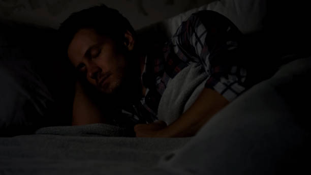 istock Male sleeping alone in dark room at night, comfortable mattress and pillows 1131889302