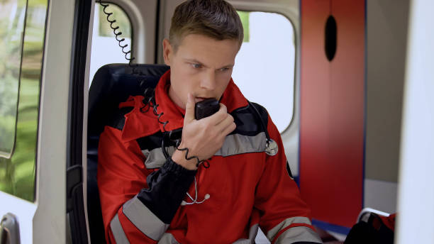 Male paramedic talking by radio, sitting in ambulance, ready to drive on call Male paramedic talking by radio, sitting in ambulance, ready to drive on call dispatcher stock pictures, royalty-free photos & images