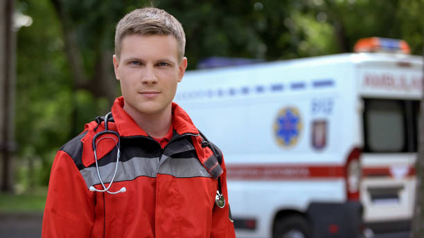 istock Male paramedic posing for camera, ambulance on background, professionalism 1131889463