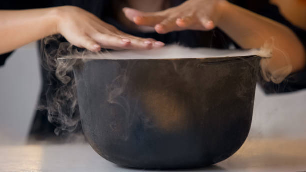 istock Witch in black dress and cloak making witchcraft over magic potion, Halloween 1131890061