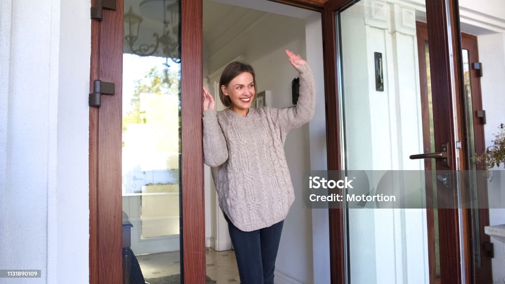 Mother standing by door and waving hand to children walking to school, goodbye Waving - Gesture Stock Photo