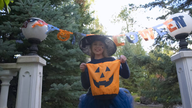 istock Little witch holds Trick or Treat bag, asks for sweets outdoors, Halloween party 1131890213