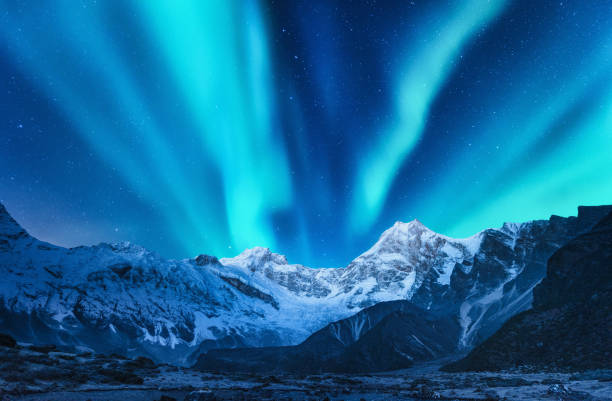 Aurora borealis above the snow covered mountain range in europe. Northern lights in winter. Night landscape with green polar lights and snowy mountains. Starry sky with aurora over the rocks. Space Aurora borealis above the snow covered mountain range in europe. Northern lights in winter. Night landscape with green polar lights and snowy mountains. Starry sky with aurora over the rocks. Space brightly lit winter season rock stock pictures, royalty-free photos & images