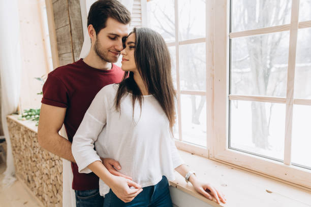 istock Attractive couple is standing near a window, they sensual hugging each other 1131891649