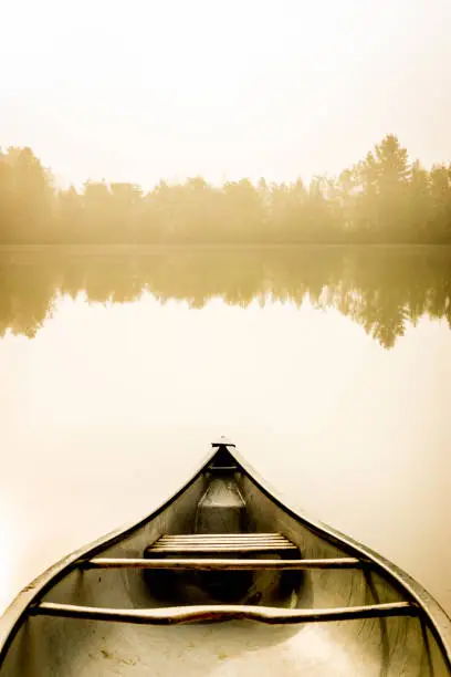 Photo of Peaceful fishing lake and canoe at sunrise.