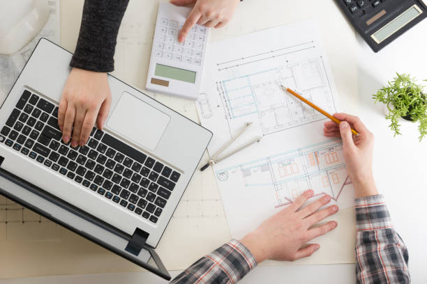 istock Architects working on blueprint, real estate project. Architect workplace - architectural project, blueprints, ruler, calculator, laptop and divider compass. Construction concept. Engineering tools. 1131895369