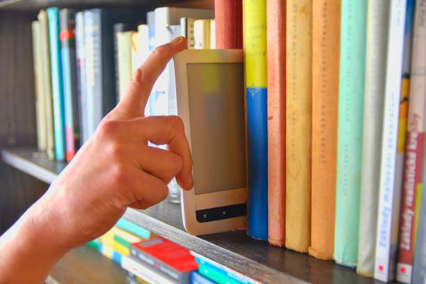 Electronic book picked from a library shelf. The electronic book on a bookshelf among the many books in the library. Books and library concept