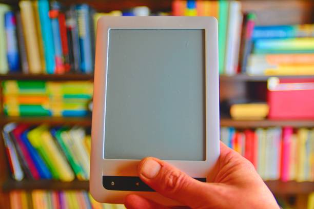 istock E-book or digital reading tablet device. E-book in man's hand. On the background is the shelf with bright real books. Online shopping books concept 1131898137