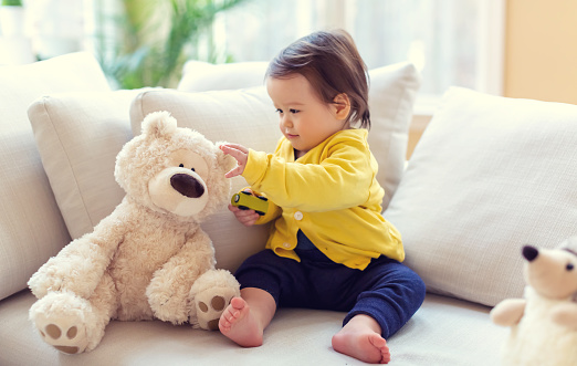 Toddler boy playing with a teddy bear in his house