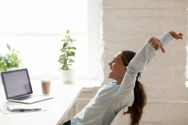 cheerful woman stretching raising hands up sitting at workplace - great discounts imagens e fotografias de stock