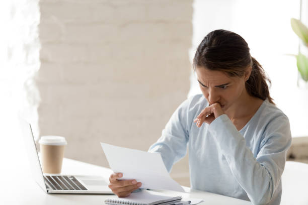 istock Frustrated young woman sitting at table reading letter 1131901017