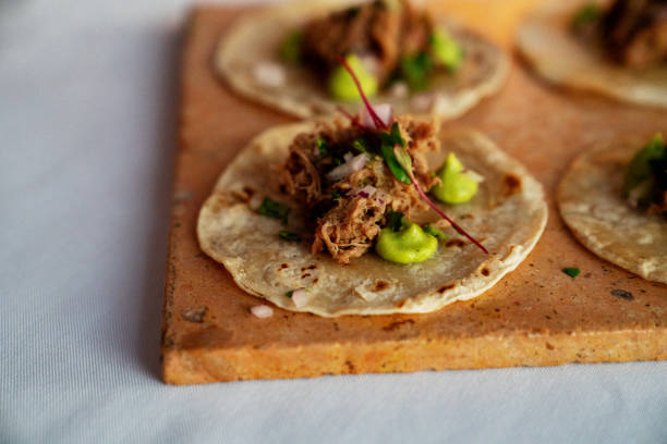 tacos de ternera rallado bellamente estilo en tortillas de maíz con puntos de guacamole - taco alimento fotografías e imágenes de stock