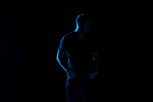 istock Handsome man with black shirt with colored gel lighting 1131917852