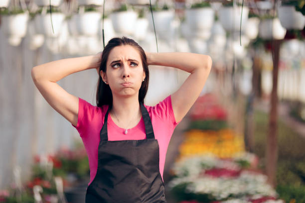 Tired Female Worker in Floral Greenhouse Feeling Overwhelmed Stressed business owner having a bad season in agricultural field of work minimum wage stock pictures, royalty-free photos & images