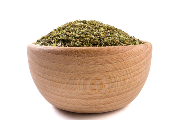 istock marjoram herb in wooden bowl isolated on white background. 1131923708