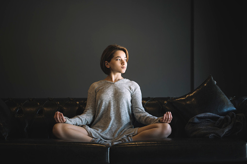 Woman meditating on the leather sofa