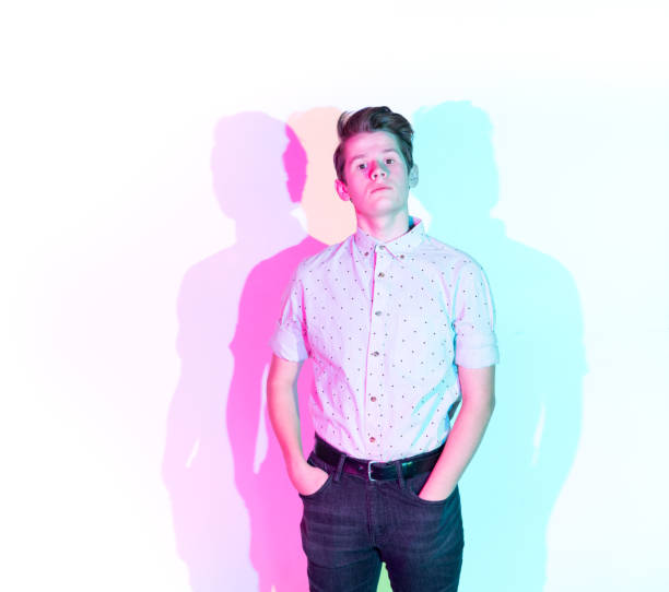 Handsome young man standing against white wall with colorful shadows