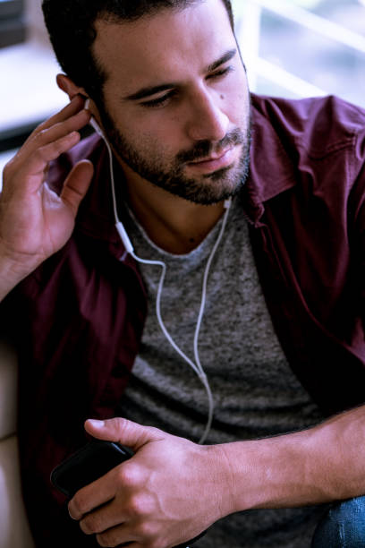 Male portrait of fashion black man indoors, dark background with copy space. Person of color wear rose sweater, white shirt and jeans.
