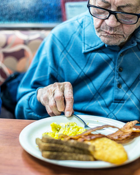 istock Elderly Arthritic Man Restaurant Diner Eating Scrambled Eggs Breakfast 1131943288