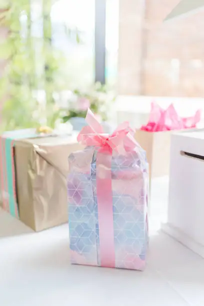Beautifully wrapped gift with large pink bow sitting on a gift table
