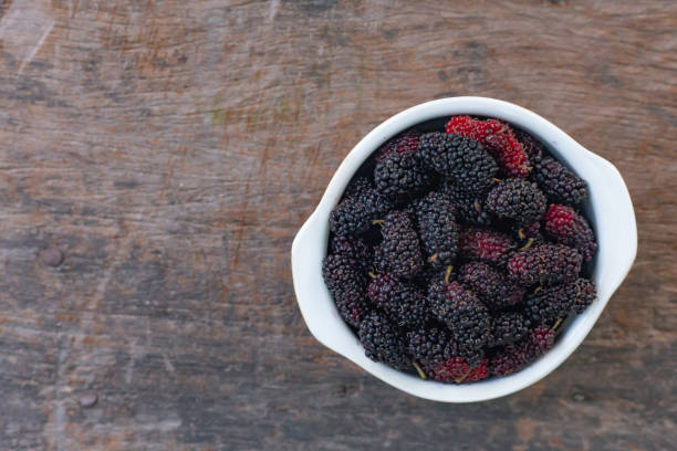 istock The mulberry fruit in white bowl on wood table. 1131947521