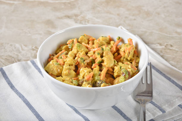 A bowl of curried chicken salad with carrots, onions, cashews, raisins and honey