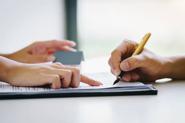 istock Estate agent pointing finger on document showing where to sign. Signing a paper document for buying house.Real estate, home loan and insurance concept 1131959746