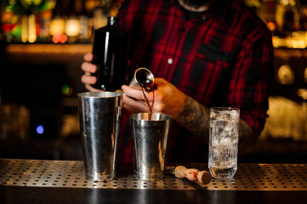 istock Bartender pouring a drink making cocktail from the steel jigger to the steel shaker 1131959940