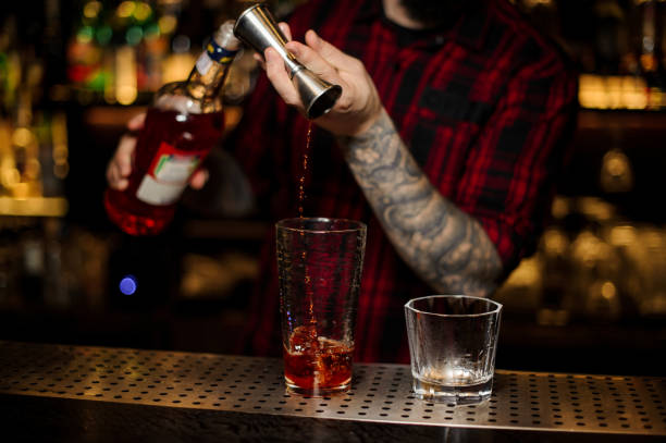 istock Bartender pouring a drink making Foreign Legion cocktail from the steel jigger to the measuring cup 1131959990