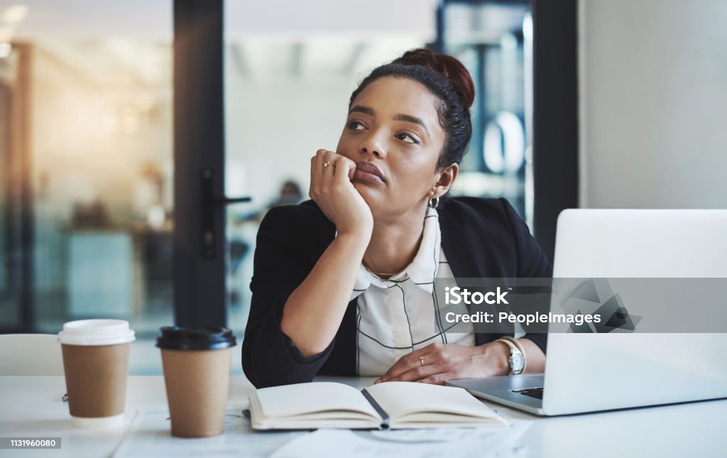 Maybe I'm not meant for a desk job Shot of a young businesswoman looking bored while working at her desk in a modern office Boredom Stock Photo