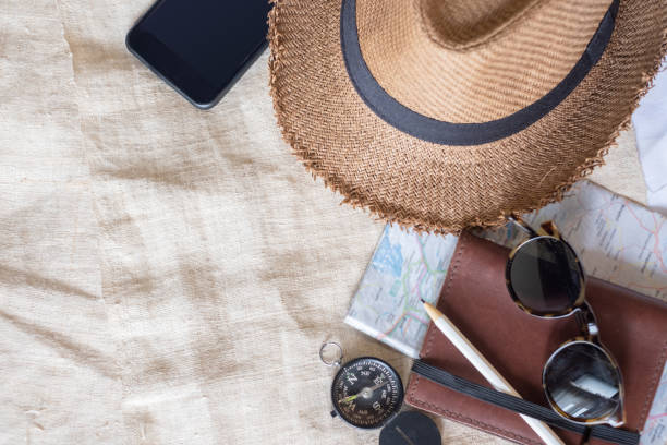 istock Top view of Summer brown panama straw hat,mobile,sunglasses,notebook map,compass on linen cloth.vacation travel concept.copy space for adding text. 1131960245