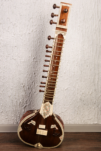 Indian musical instrument sitar standing next to the grey wall - image