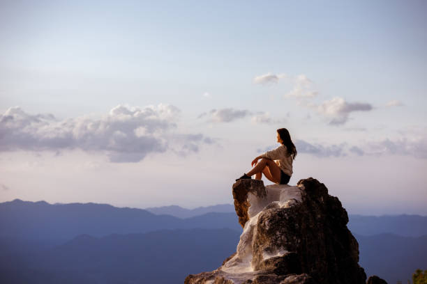 istock Beautiful girl sits big rock at sunset 1131962944
