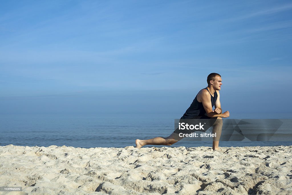 Młody człowiek ćwiczyć na plaży. - Zbiór zdjęć royalty-free (Dorosły)