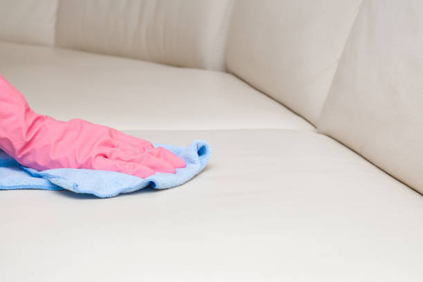 istock Cleaner hand in rubber protective glove wiping light gray eco leather sofa with rag. General or regular cleanup. Commercial cleaning company. Close up. 1131965836