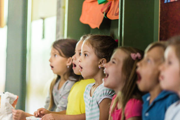 Group of elementary students singing in choir at school. Large group of students singing in a choir during music class at elementary school. school choir stock pictures, royalty-free photos & images