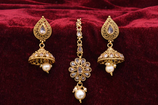 istock Fancy Designer golden earrings closeup macro image on red background 1131973801