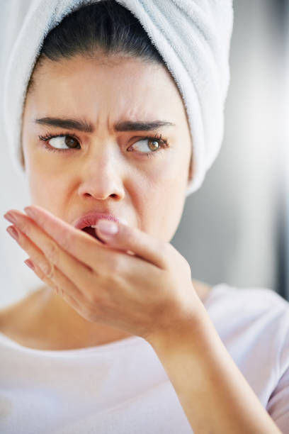 Is that smell coming from me? Shot of a beautiful young woman checking her breath at home woman wrapped in bath towel stock pictures, royalty-free photos & images